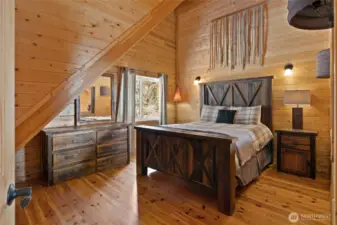 Upstairs, this bedroom has a fun "hayloft" feel with antique Texas barnwood doors over the window that looks over the loft/great room below!
