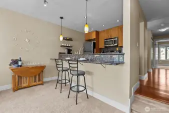 When you come through the entryway, the hallway floors are gleaming from the light coming through the primary bedroom windows (west-facing).   Also pictured is a granite slab eating bar that easily seats 4.  The space is also suitable for a small dining room table.  I really like the sunken living room that puts the eating bar lower than the kitchen.