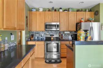 Kitchen has granite countertops, oak cabinets, real hardwood floors, tile backsplash, stainless steel appliances too!