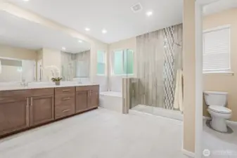 The Primary Bath  features custom tile, quartz counters and a frameless walk-in shower.
