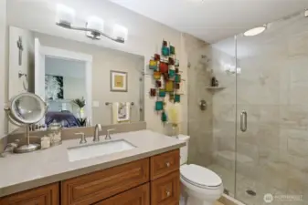 Your private primary bath features an elongated toilet, full ceiling-height tile walk-in shower with glass door, great cabinet storage and quartz countertops.