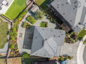Aerial view directly overhead of property. From here you can see the fire pit area, the large patio, the flower and raspberry beds, the garden shed (in the top fenced in corner), the pet care area, and the different landscaping with low maintenance plants.