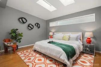 The main-floor primary bedroom easily accommodates a king bed.  Two skylights and a frosted clerestory deliver natural light without compromising privacy.