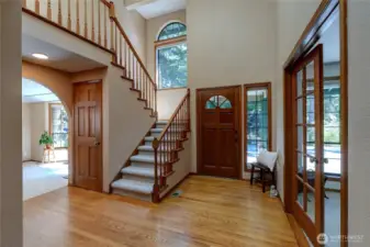 Grand Entry-Oak Wood Staircase Surrounded By Walls Of Windows & Unblemished Hardwood Floors