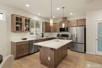 Shadow stained maple cabinets and quartz countertops grace the kitchen.