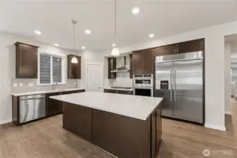 Gourmet kitchen with upgraded appliances including 48" built-in fridge, gas cooktop, standalone vent, wall oven and microwave.  Photos are representational. Actual colors and finishes will vary. See site agent for details.