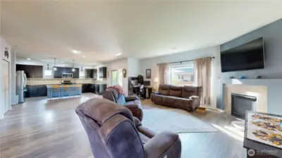 Spacious great room featuring a gas fireplace with tile surround and large windows for natural light