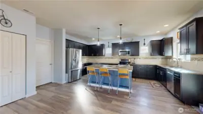 Gourmet kitchen featuring a large center island, quartz counters, stainless steel appliances, and pantry.