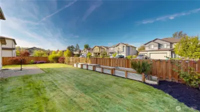 Fully fenced backyard with raised garden beds