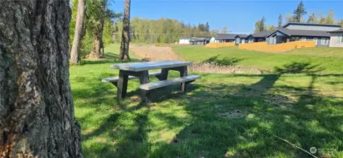 Picnic area near the entrance with storm water pound in the background and a paved walking path on the right.