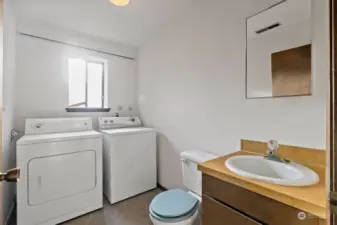 The downstairs utility room with a half bath, also has newly installed flooring.