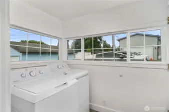 Tucked just off the kitchen, this laundry room is wrapped in windows—filling the space with natural light and making everyday chores feel a little less like work. A practical setup with washer and dryer included, it’s a cheerful and functional bonus to this charming home.