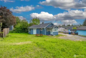 This wider perspective shows off the generous yard space—perfect for gardening, play, or future projects. The home sits with alley access and features two entry points: a side door leading into the living area and a front entry through the mudroom/laundry area. The vibrant blue exterior adds charm, while the picnic table invites you to enjoy outdoor moments in your own slice of Tacoma.