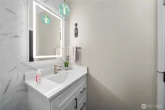The powder room’s angled tile wall adds a striking, artistic flair.