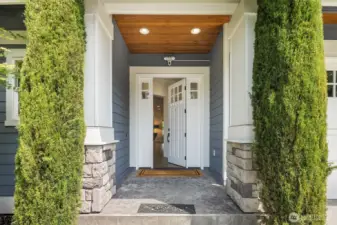 Step inside through a charming covered entry framed by stone columns and crisp white millwork—where timeless curb appeal meets a warm, welcoming interior.
