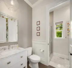Thoughtfully designed main floor bath featuring a marble-topped vanity, stylish tilework, and a light-filled walk-in shower. Dual access from both the main living area and the adjacent bedroom allows for flexible use—easily functions as a powder room day-to-day, or opens up as a full guest bath when needed.
