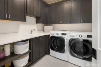Plenty of elbow room for laundry day—this spacious utility room features extensive cabinetry, deep counters for folding, a soaking sink, and side-by-side LG washer and dryer. Thoughtfully designed to keep household chaos under control.