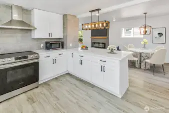 Virtually staged. View of kitchen and dining room with a peak of the fireplace.