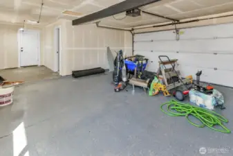 2 car main garage with views of doorway into office space and another door into gravel enclosed 3rd car bay/shop.