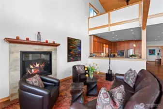 This sitting area by the fireplacet is located next to the open kitchen. One of two primary suites is just above. The pony wall provides privacy for one of the primarys.