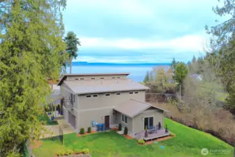 View of the rear of the home. Grass area behind the hiome runs to the tree line.