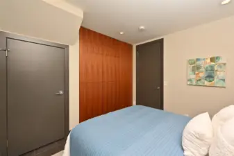 2nd bedroom with closet and storage drawers behind the walnut paneling.