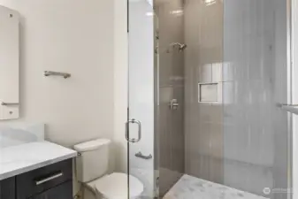 Featuring an inlaid tile niche and premium frameless shower glass door, Rush Residential spares no detail in crafting an opulent guest bathroom.