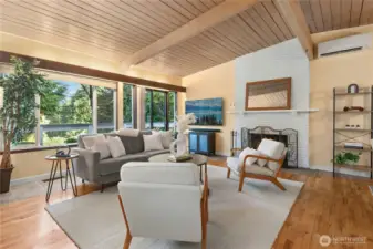 Vaulted exposed wood ceiling over large living room with frpl and wood floors