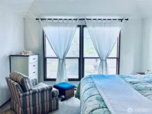 Master bedroom with large windows looking east and street