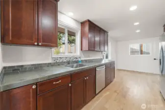 Updated eat-in kitchen featuring new sink and fixtures, upgraded lighting and hardware, plus a new refrigerator, range hood, and microwave