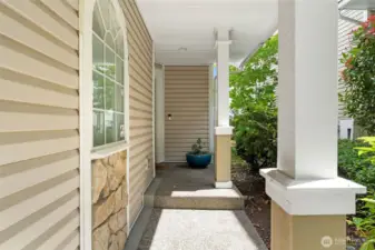 A charming covered walkway framed by mature landscaping offers a quiet, sheltered approach to the front door.