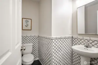 Downstairs half bath also finished in white tiles with black color.