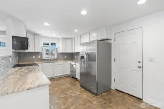 Updated kitchen with recessed lighting, brand-new white cabinets, granite countertops, designer glass backslash and stainless-steel appliances.