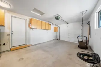 Garage with cabinets and man door into the kitchen.