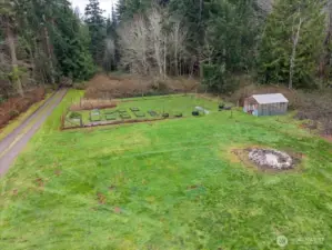 Large open yard space with numerous garden beds and a greenhouse.