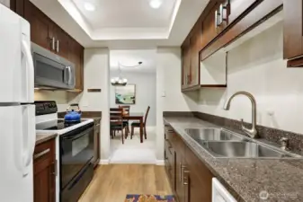 The kitchen has quartz counters and wood cabinets with extra storage drawers inside for maximum storage.