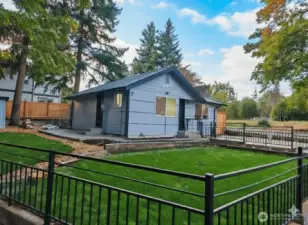 Peaceful curb appeal with clean lines and open space — freshly updated exterior, new siding, manicured lawn, and a private fenced yard. The setting feels calm, modern, and move-in ready.