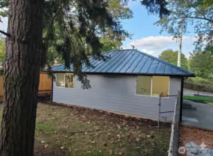 Back view of the home featuring two bedroom windows and a fully fenced backyard area — ideal for pets, a garden, or a private outdoor nook. Includes a separate gated section that works perfectly as a dog run.