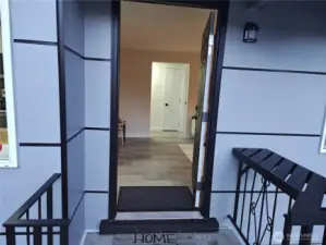 Welcoming front entry with a freshly painted door and a modern black railing — offering a first glimpse into the bright, updated interior.