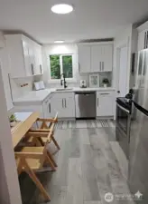 Modern kitchen with quartz countertops, soft-close white cabinetry, stainless steel appliances, and a cozy breakfast nook filled with natural light.