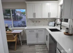 Bright and elegant kitchen with quartz countertops, stylish backsplash, and a dining nook by a large picture window bringing in natural light and neighborhood views.