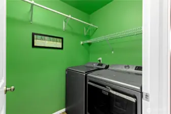 Dedicated laundry room with shelving and space for storage, adding everyday convenience.