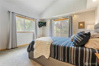 Primary bedroom upstairs with vaulted ceilings and ceilings and tons of natural light