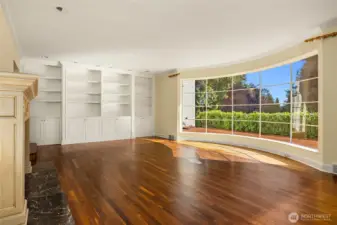The home is currently vacant, and this is the ivinng room.  Big bay window floods this room with sunshine. Built-in bookshelves and a wood burning fireplace.