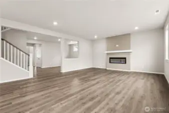 Wide angle view of Great Room, Dining Area and Staircase Railing Detail and Fireplace.