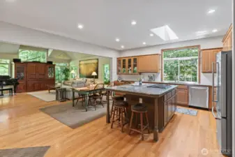 The spacious and functional kitchen features a large island with bar seating, under-cabinet lighting, skylight, walk-in pantry and stainless-steel appliances including a new refrigerator (2025), high-end Wolf range/oven (2022), and a sleek 3-in-1 microwave, convection oven, and air fryer for modern versatility. Seamlessly connected to a cozy sitting area with fireplace, a casual dining space, and the expansive family room, this space is perfect for everyday living and effortless entertaining.