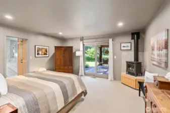The primary suite offers a cozy Hampton stove for added warmth and ambiance, a sliding glass door that opens directly to the spectacular covered deck, Hunter-Douglas window treatments, and a custom walk-in closet with a skylight and California Closet system. The spacious en-suite bathroom features double sinks, a jetted soaking tub, private toilet closet and marble (heated) flooring, counters and tub/shower surround.