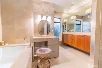 Another view of the primary bath with the large tub, vanity, and two sinks.