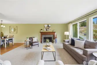 The living room features a wood burning fireplace and large windows that bring in a lot of light. Dining room visible to the left.