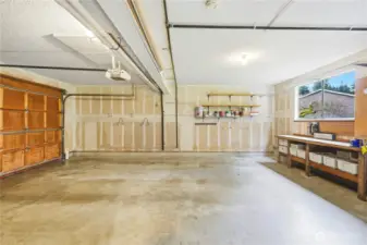 The large two-car garage with work bench enjoys access to the yard (door to right not in photo).